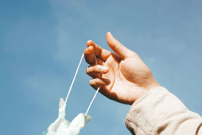 Low angle view of hand holding blue sky