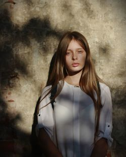 Portrait of beautiful young woman standing against wall