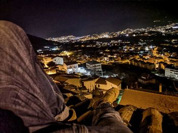 Low section of man by illuminated buildings in city at night