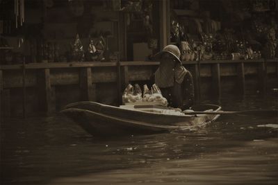 Rear view of woman sitting on boat in canal