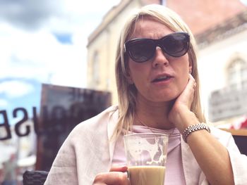 Portrait of woman wearing sunglasses while having coffee