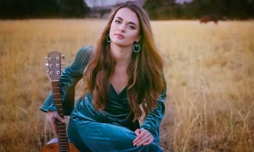 Portrait of beautiful young woman sitting on field