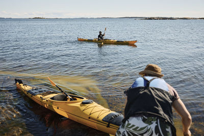 Man on coast pushing kayak on water