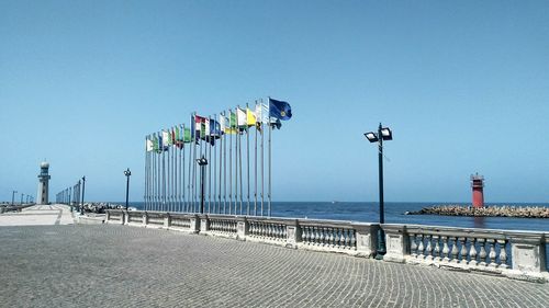 Flags at beach against clear blue sky