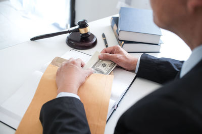 Midsection of judge putting money in envelope on table