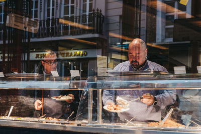 Reflection of man and food in glass