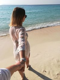 Rear view of woman standing on beach against clear sky