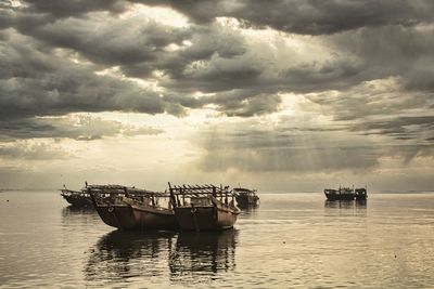 Fishing boat in sea against sky during sunset