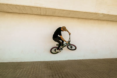 Man riding bicycle against wall