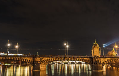 Illuminated bridge over river against sky at night