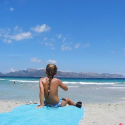 Rear view of shirtless girl on beach against sky holiday