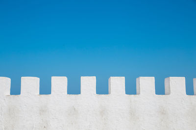 Low angle view of white wall against blue sky