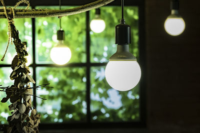 Illuminated light bulb hanging from ceiling