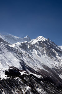 Scenic view of snowcapped mountains against clear blue sky