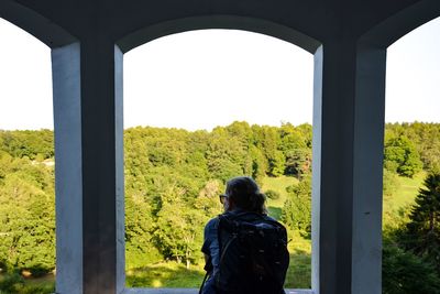 Rear view of woman looking at view while standing by window