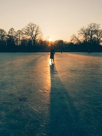 Silhouette of man on snowy field during sunset