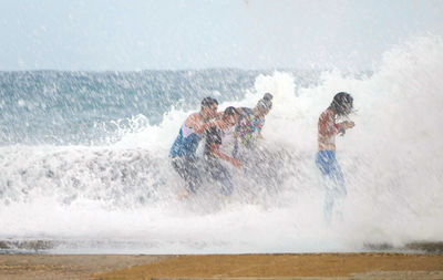 People enjoying waves splash at beach