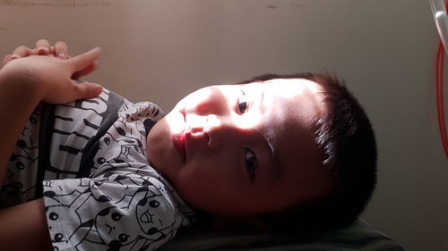 Portrait of cute boy lying on bed at home