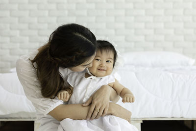 Rear view of mother and daughter on bed