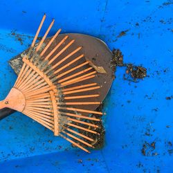 Close-up of rake and spade on blue surface