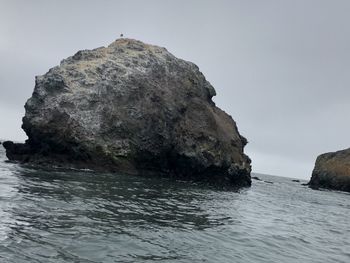 Rock formation in sea against clear sky
