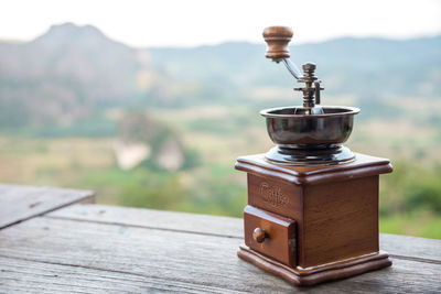 Close-up of coffee maker on table against mountain