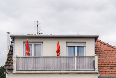 Front view of red umbrellas on a balcony. low angle view of building against sky 