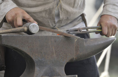 Midsection of man working on metal in workshop