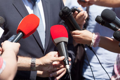 Cropped image of reporters taking interview of speaker