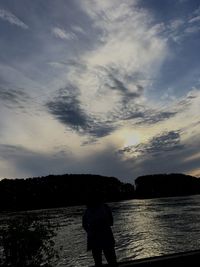 Silhouette of woman in sea at sunset