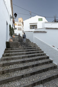 Low angle view of woman walking on steps amidst houses