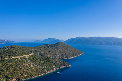 Scenic view of lake and mountains against clear blue sky