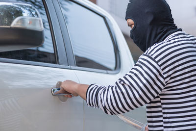Thief with knife holding car door