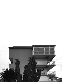 Low angle view of hand against built structure against sky