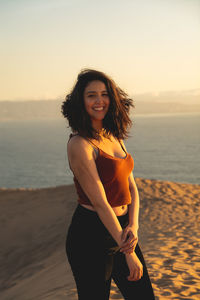 Portrait of smiling young woman standing on beach