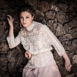 Portrait of young woman standing against stone wall
