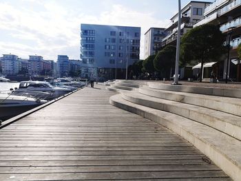 Sidewalk amidst buildings in city against sky
