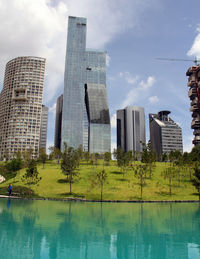 Reflection of buildings in lake against sky in city