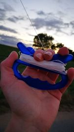 Close-up of hand holding sunglasses against sky