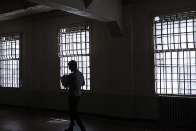 Rear view of woman standing against window in building