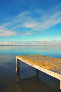 Swimming pool by sea against blue sky