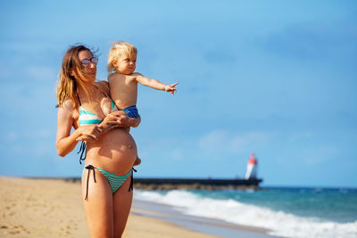 Rear view of young woman in bikini standing at beach