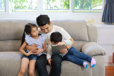
father and kids sitting on sofa at home
