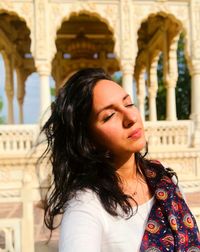 Beautiful woman with eyes closed standing against historical building