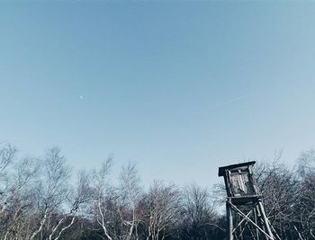 Low angle view of bare trees against clear blue sky