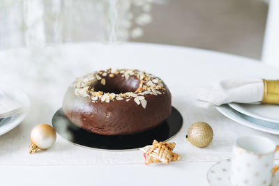 Large round chocolate almond cake on table with new year serving, christmas white scandinavian 