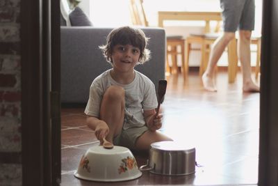 Portrait of cute boy banging kitchen utensils at home