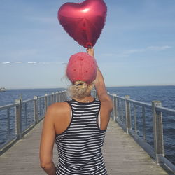 Midsection of woman standing by sea against sky