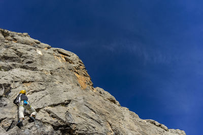 Low angle view of man on rock against blue sky