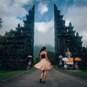 Rear view of woman standing outside building against sky